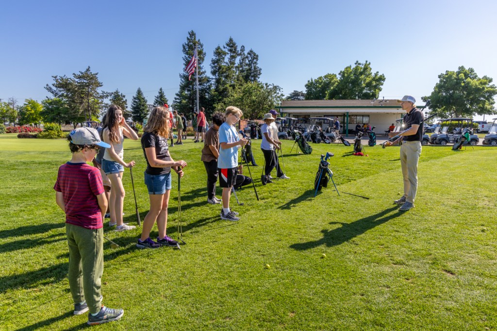 Young golfers listen attentively to the golf instructor.